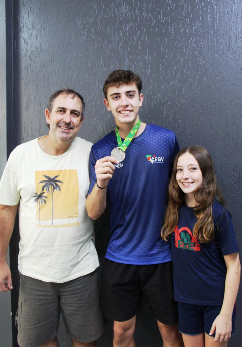 Lucas exibindo, orgulhoso, a medalha da competição. Na foto, com o pai Fábio e a irmã Sofia