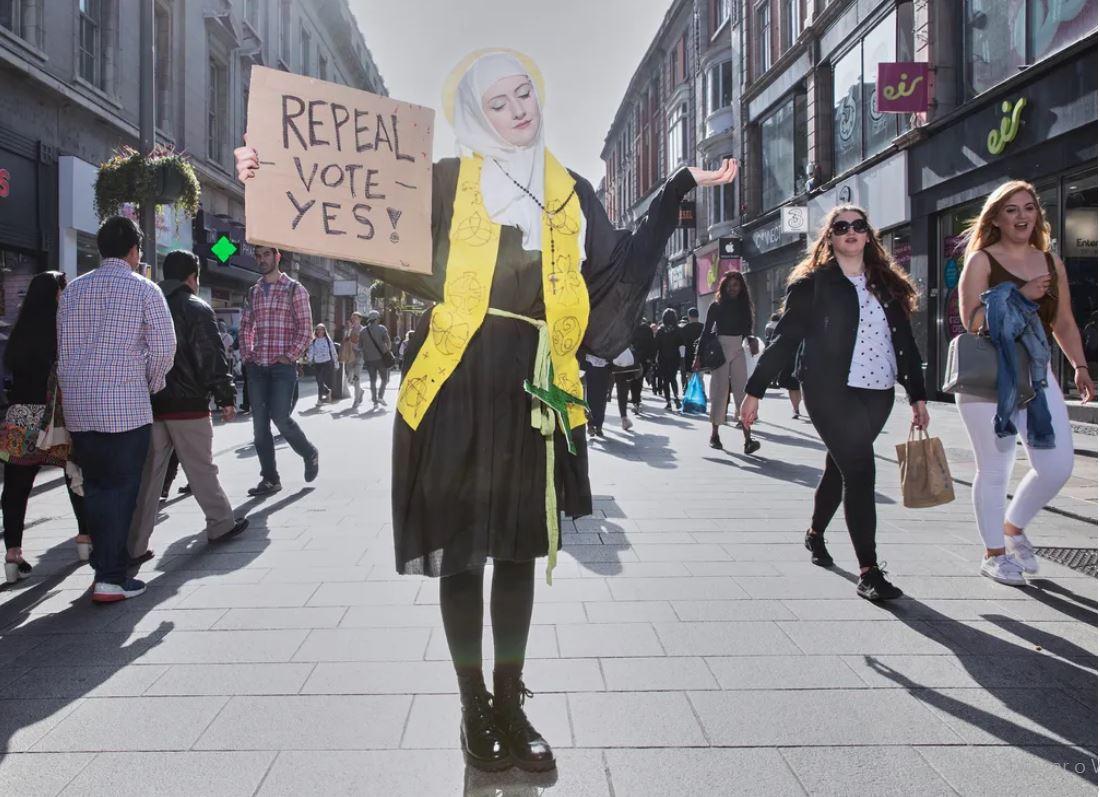 Mulher segura cartaz pedindo voto a favor de regras menos rígidas contra o aborto na Irlanda