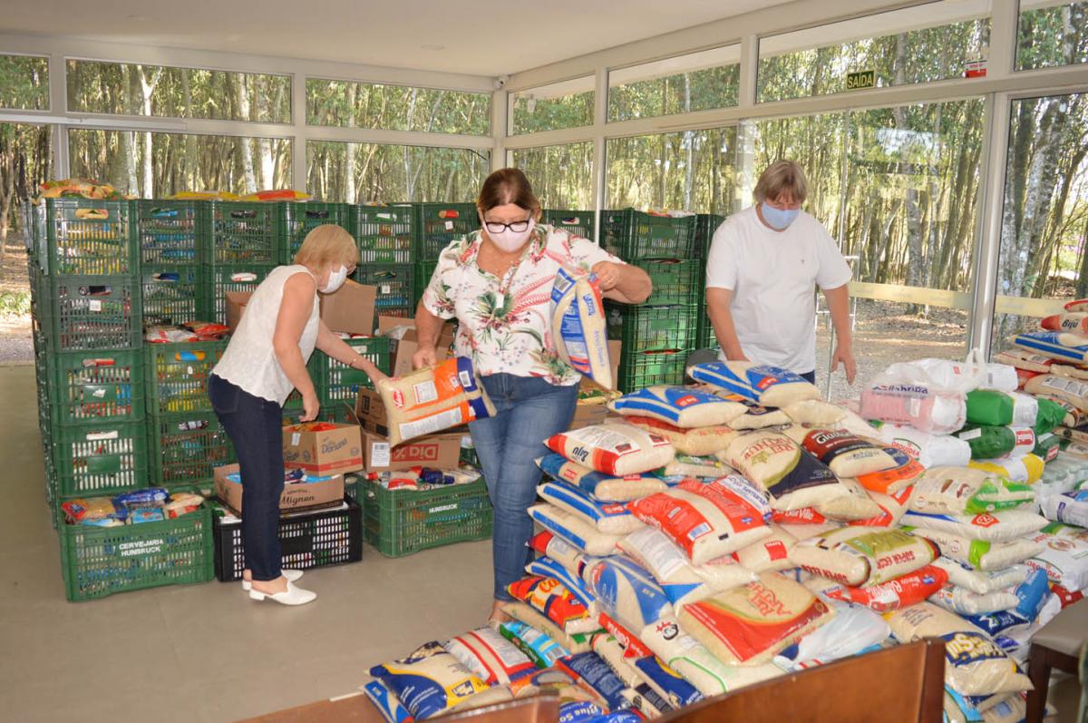 Voluntárias Ieda e Neusa separando os alimentos com Miguel, da cervejaria