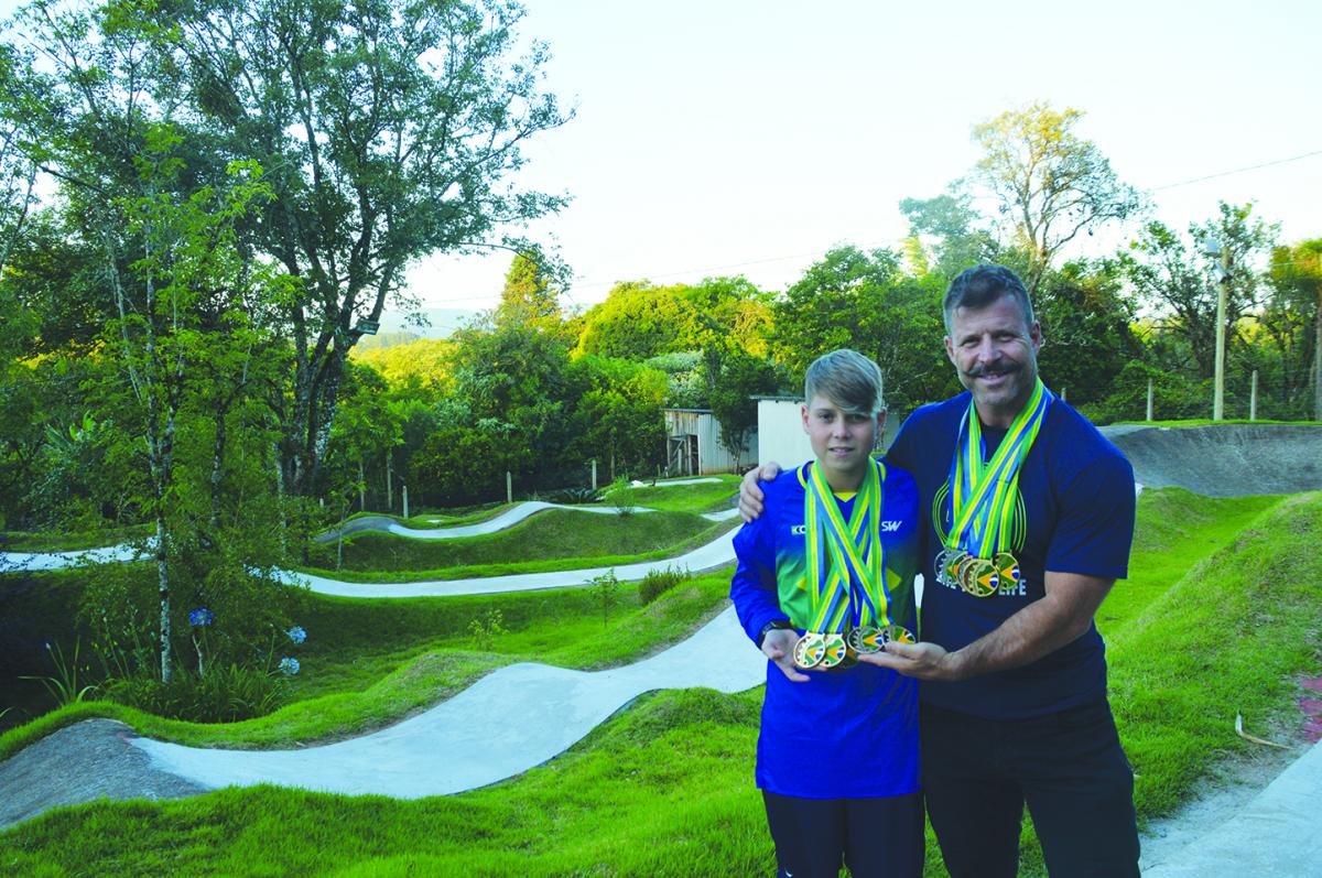 Pietro e Edson mostram orgulhosos as medalhadas conquistadas nos últimos anos. Ao fundo, a pista exclusiva, no pátio de casa