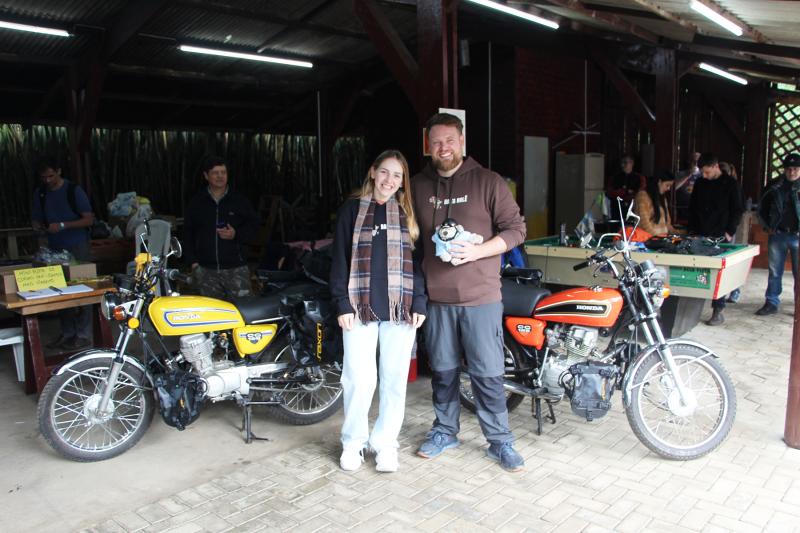 Jussara e Gustavo com o mascote Juca em frente às motos da década de 70, com as quais irão encarar a aventura na África