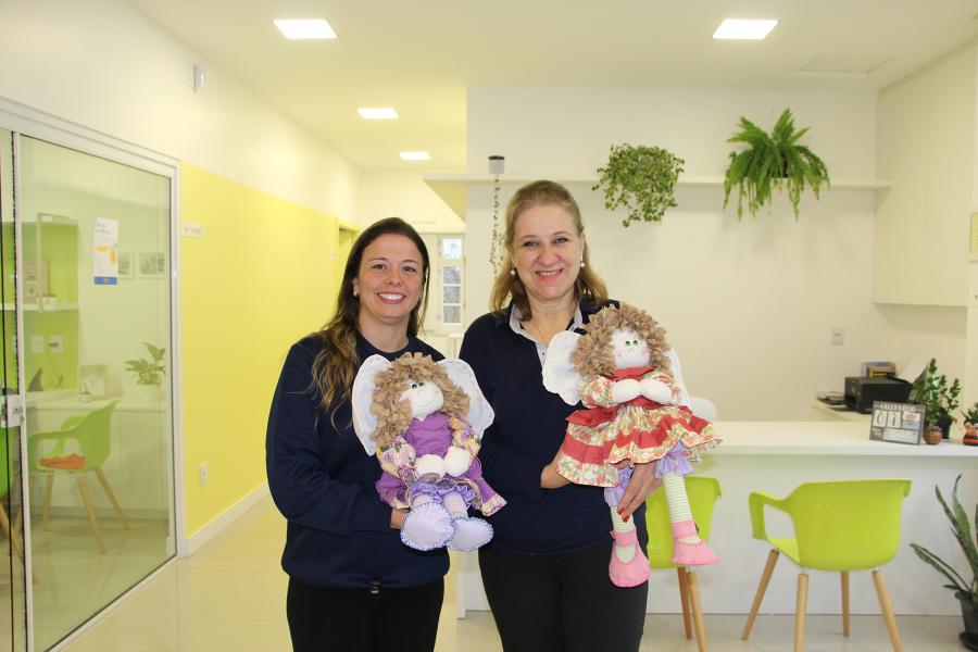 Psicóloga Lizandra Loureiro Pinto e a diretora Luciana Lemos com a boneca Verinha, mascote do Instituto Olívia do Bem